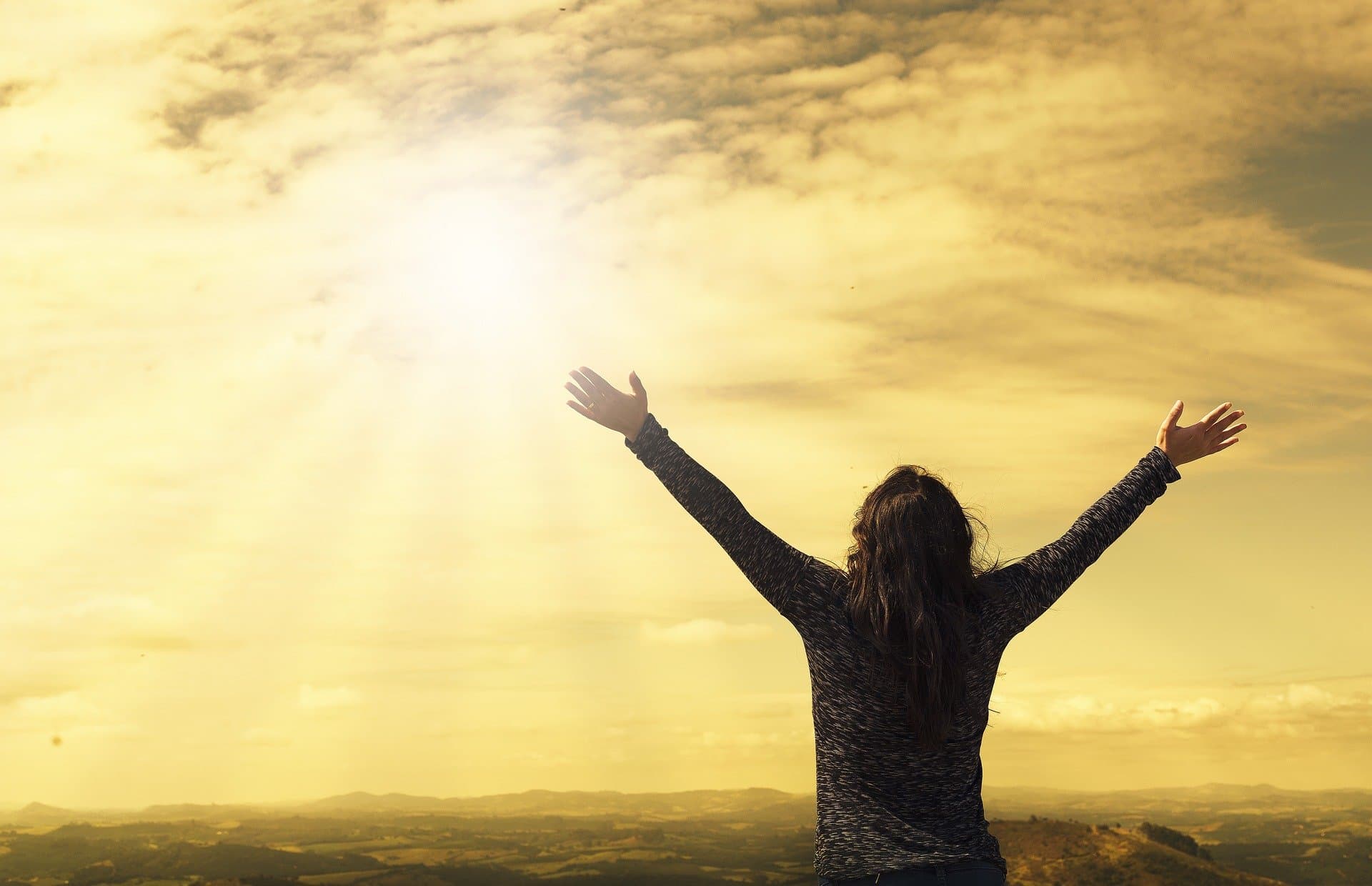 Woman with arms raised in golden sunlight embracing freedom and healing